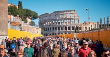 Tourists walk by the famous Colosseum on a sunny day.