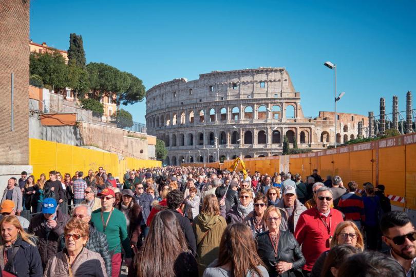 Tourists walk by the famous Colosseum on a sunny day.
