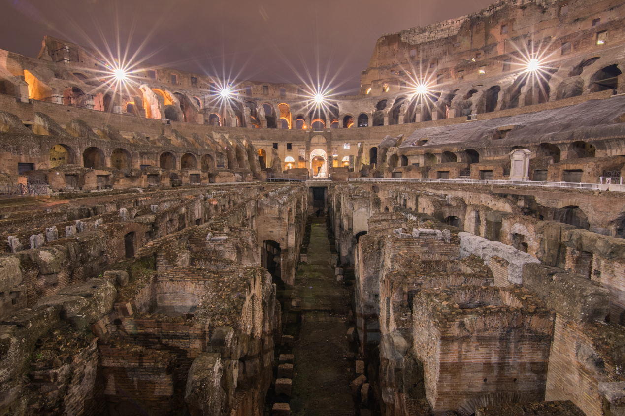 A night photography of the interior of the Colosseum clearly showing the underfloor tunnels