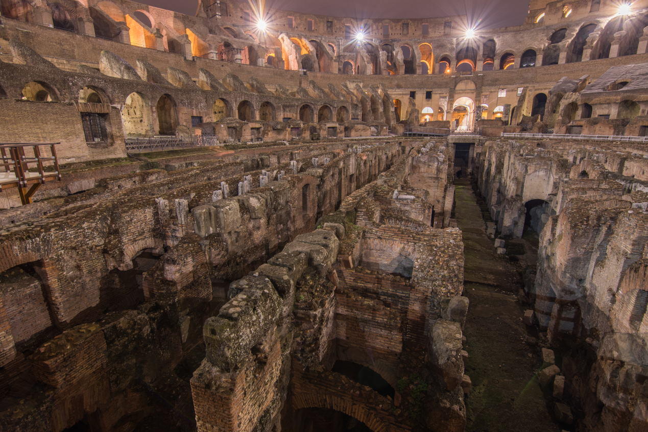 A night photography of the interior of the Colosseum clearly showing the underfloor tunnels