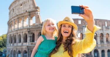 Happy mother and baby girl making selfie in front of colosseum in rome, italy