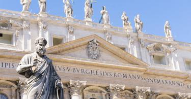 Statue of Saint Peter and Saint Peter's Basilica at background in St. Peter's Square, low angle shot, Vatican City, Rome, Italy