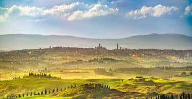 Things to do in Tuscany - Siena city panoramic skyline, countryside and rolling hills in a misty day. Tuscany, Italy, Europe.