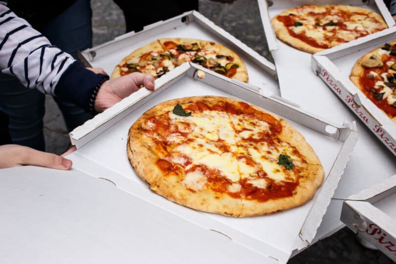 pizza Margarita in the box at the street, woman`s hands closeup, Naples, Italy