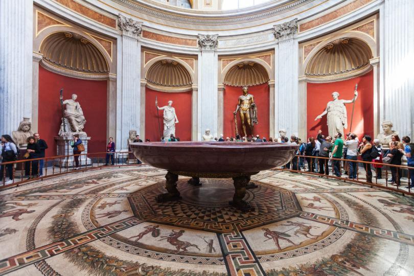 visitors near statues, Hercules figure and round monolithic porphyry basin in Round Room of Pio-Clementino Museum in Vatican museums in Vatican city