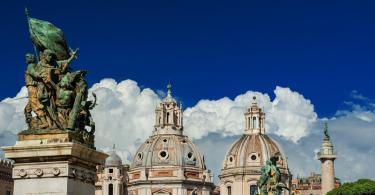 Twin Churches beautiful domes with ancient Trajan Column and clouds, seen from Altar of Nation Monument in the center of Rome