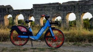 A rental electric bike parked near ancient Roman ruins in Parco degli Acquedotti, Rome.
