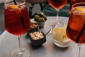 Aperol Spritz drinks with small snacks on a table during aperitivo hour in Rome