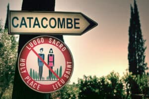 Directional sign to the San Sebastiano catacomb with a dress-code prohibition symbol._01