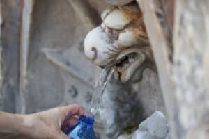 Person refilling a reusable bottle at a Roman ‘Nasoni’ public drinking fountain in Rome.