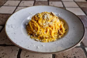 Plate of traditional Roman carbonara pasta with guanciale and pecorino cheese.